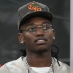 Rafa Leao in primo piano, con occhiali, cappellino ed espressione assorta